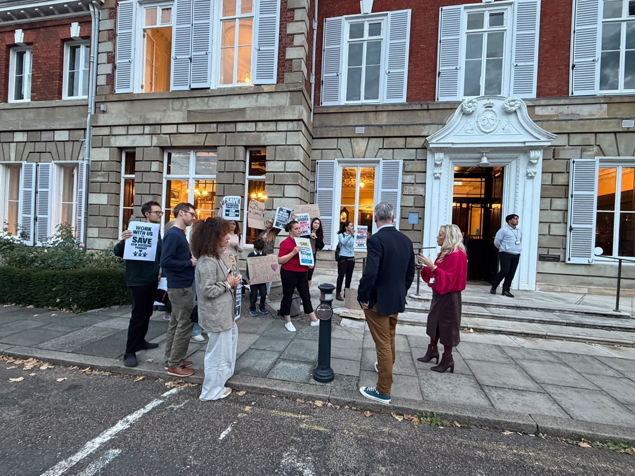 Campaign members holding Save Kew Riverside Primary School placards and speaking with council members outside York House.